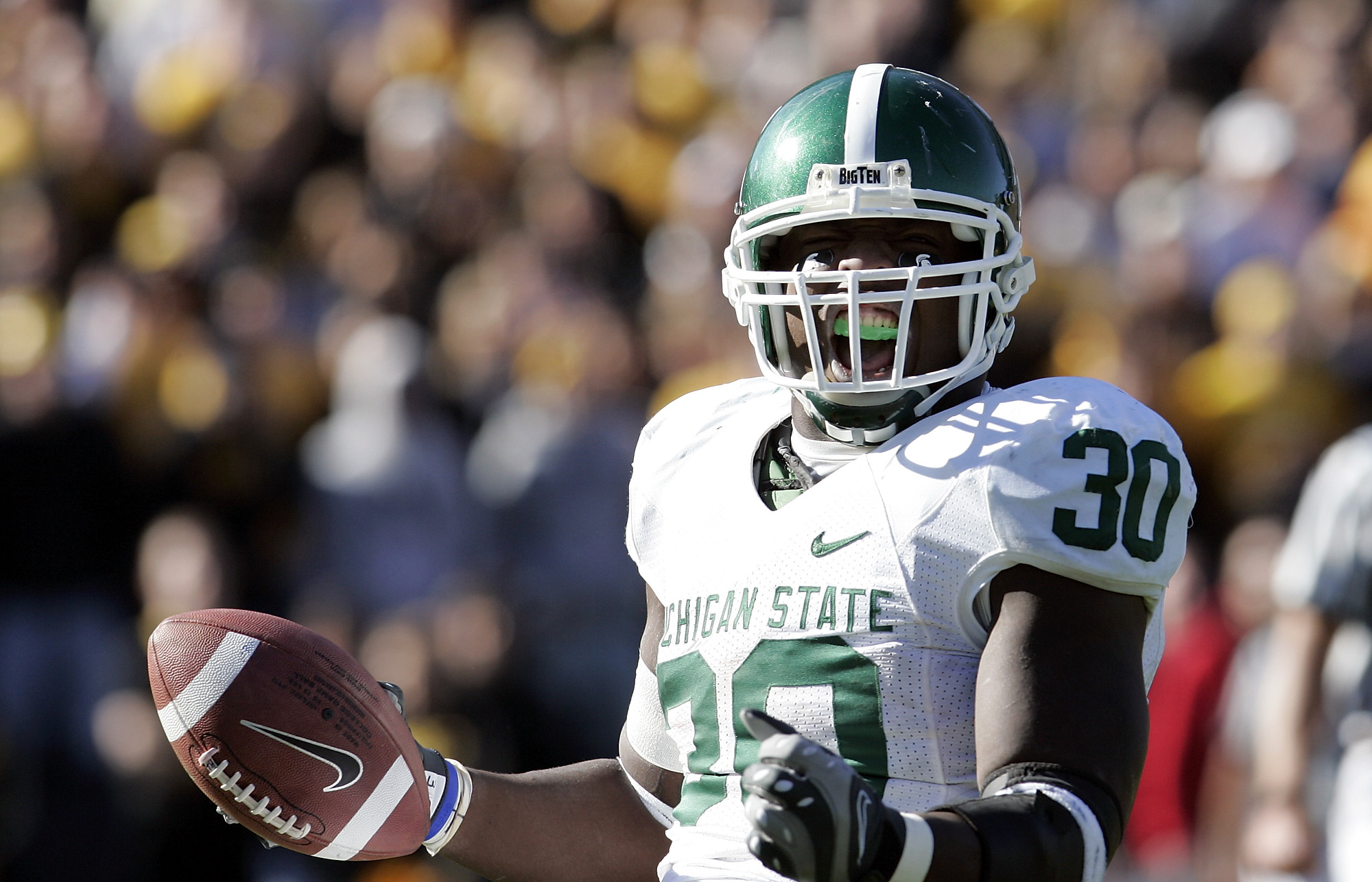 Jehuu Caulcrick #30 in Michigan State white away jersey celebrating with the ball after a touchdown