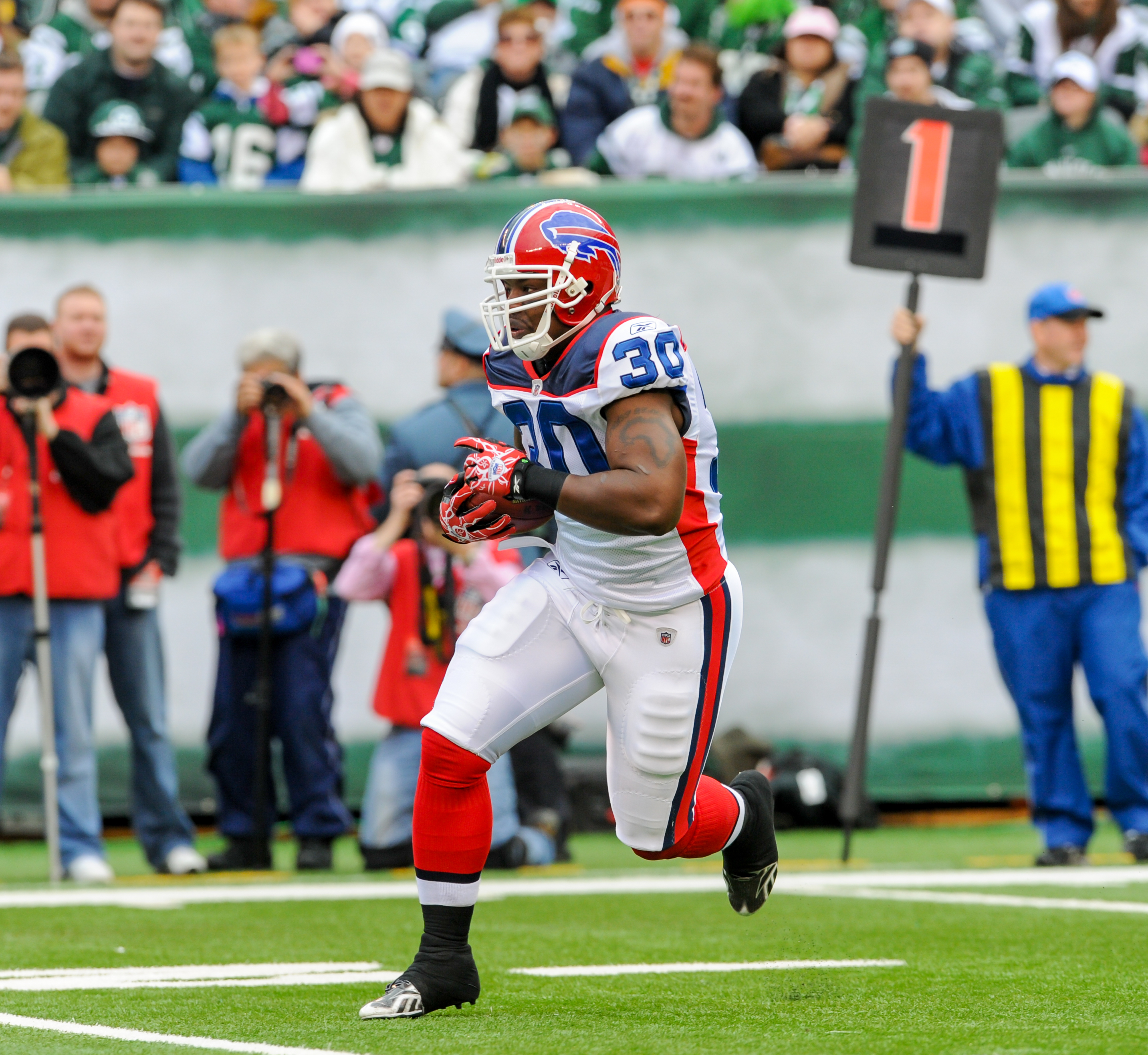 Jehuu Caulcrick #30 carrying the ball for the Buffalo Bills with a first-down marker behind him